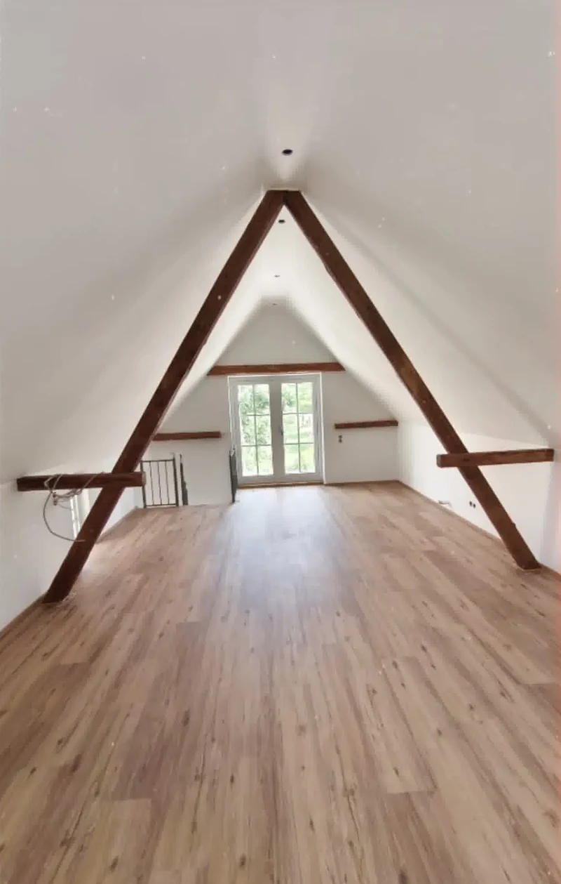Dachausbau von Damian Kosewski mit freigelegten Holzbalken und hellem Boden